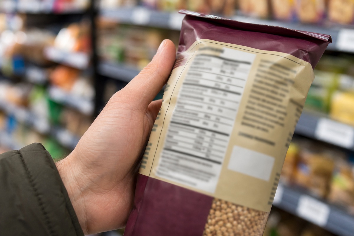 A close-up of an Australian nutrition information panel on a food packet, with a hand pointing at the protein row